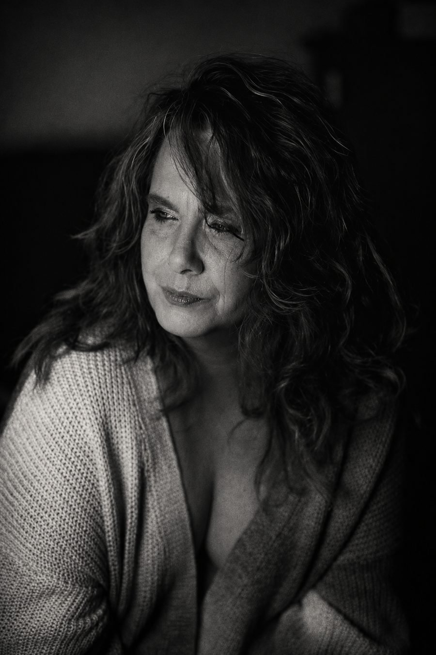 Black-and-white portrait of a woman in soft window light, looking away from the camera